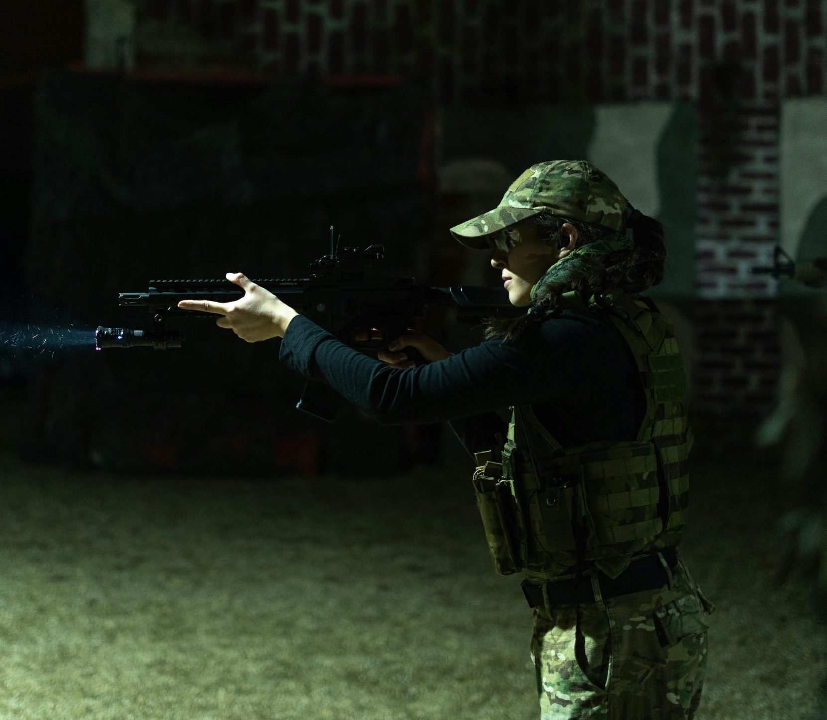 A female soldier in tactical gear aiming a weapon during night training in Timisoara, Romania.