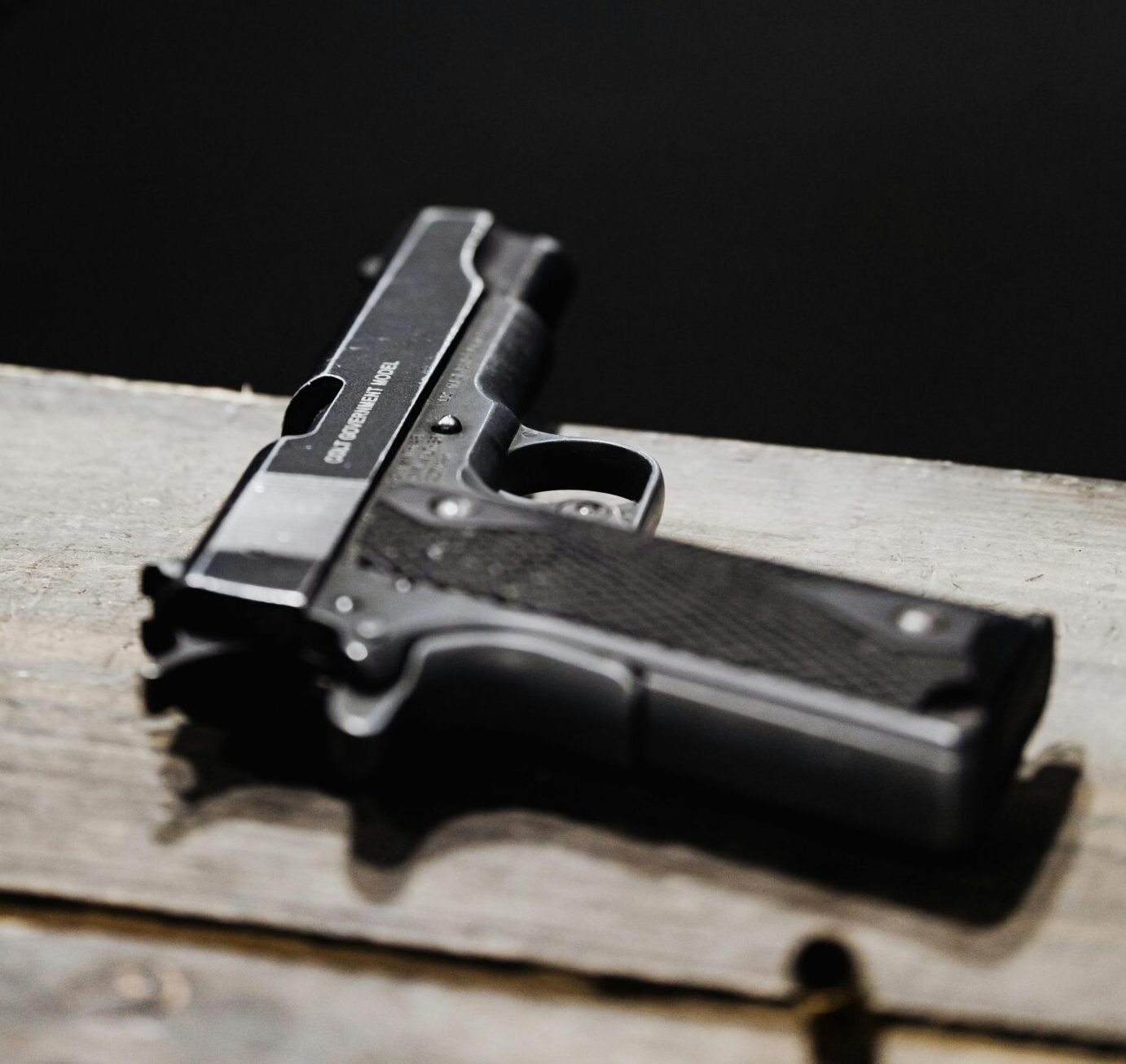 Detailed shot of a pistol placed on a wooden surface in an indoor setting.