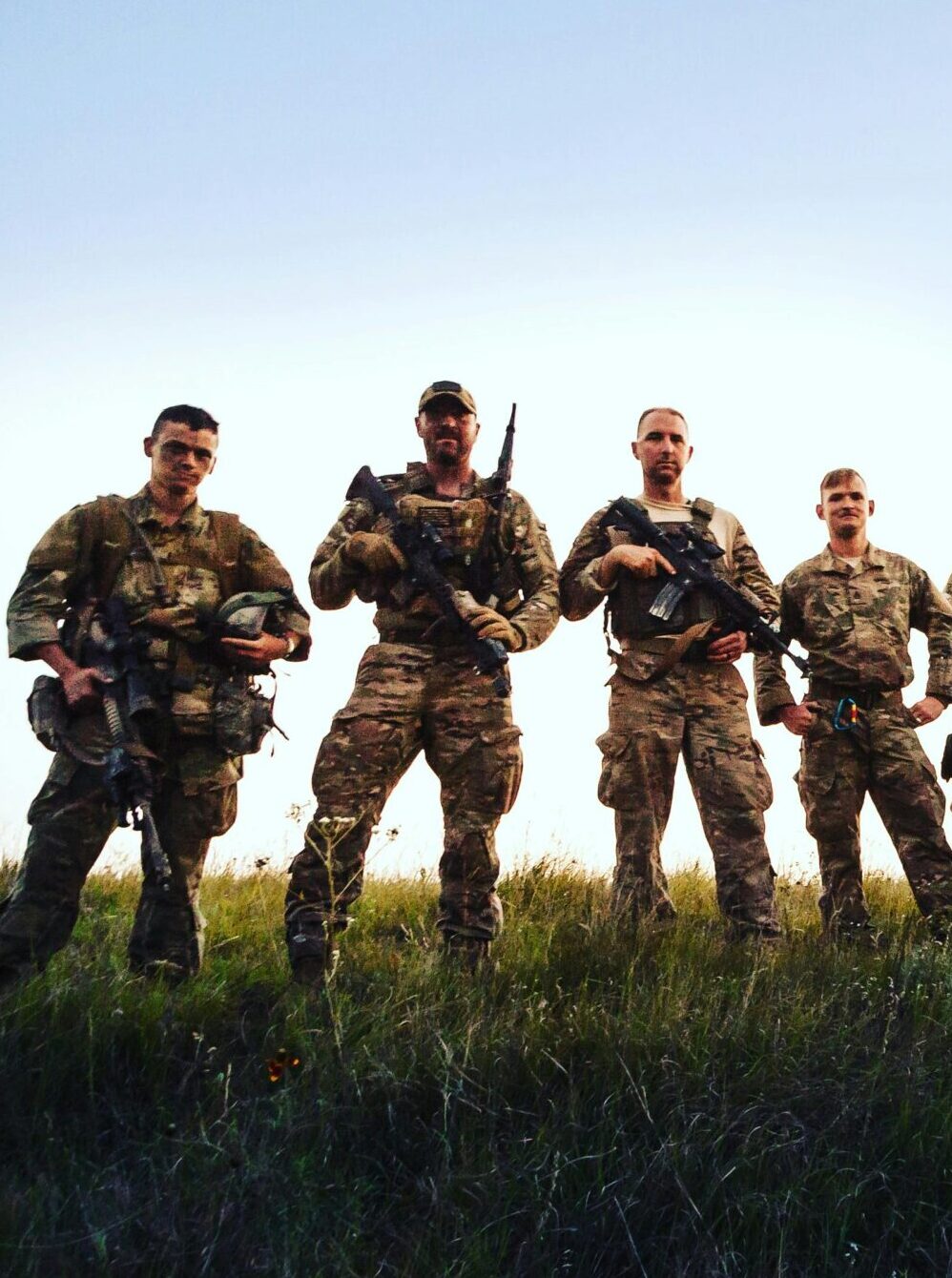 A group of soldiers in camouflage gear holding rifles on open terrain.